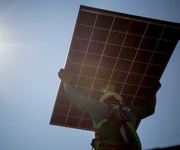 a-solarcity-corp-employee-carries-a-solar-panel