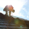 Roofer-silhouette-while-installing-shilngles-on-roof