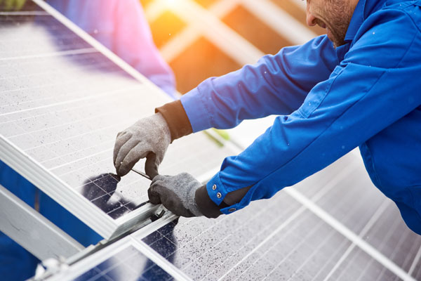 Smiling-male-technician-in-blue-suit-installing-photovoltaic